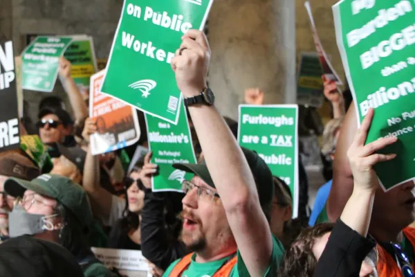 WFSE member holding a flyer that says Furloughs are a Tax on Public Workers