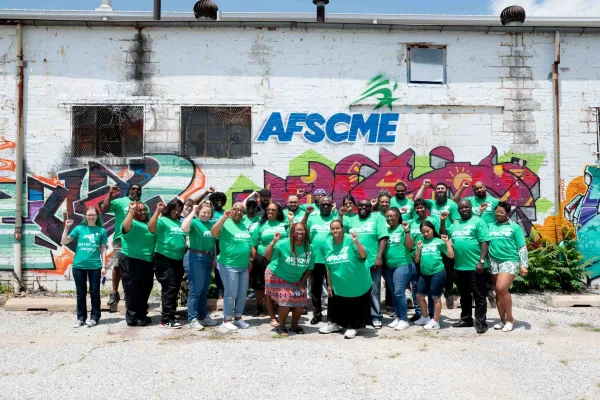 AFSCME stewards pose for a group photo in front of a wall with AFSCME graffiti artwork