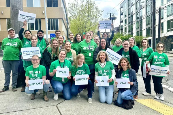 WFSE Local 889 members hold signs saying "Support Staff Support Us All!" on a street corner