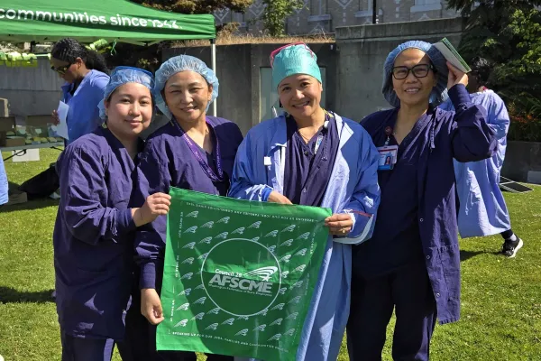 UW Members at Harborview hold up a WFSE bandana in their scrubs