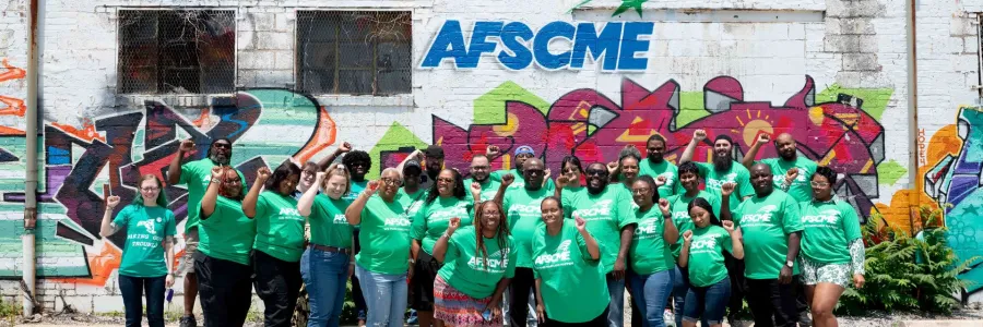 AFSCME stewards pose for a group photo in front of a wall with AFSCME graffiti artwork