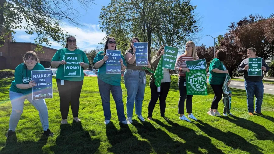 WFSE DCYF members holding Walkout for Washington signs while standing on sunlit grass
