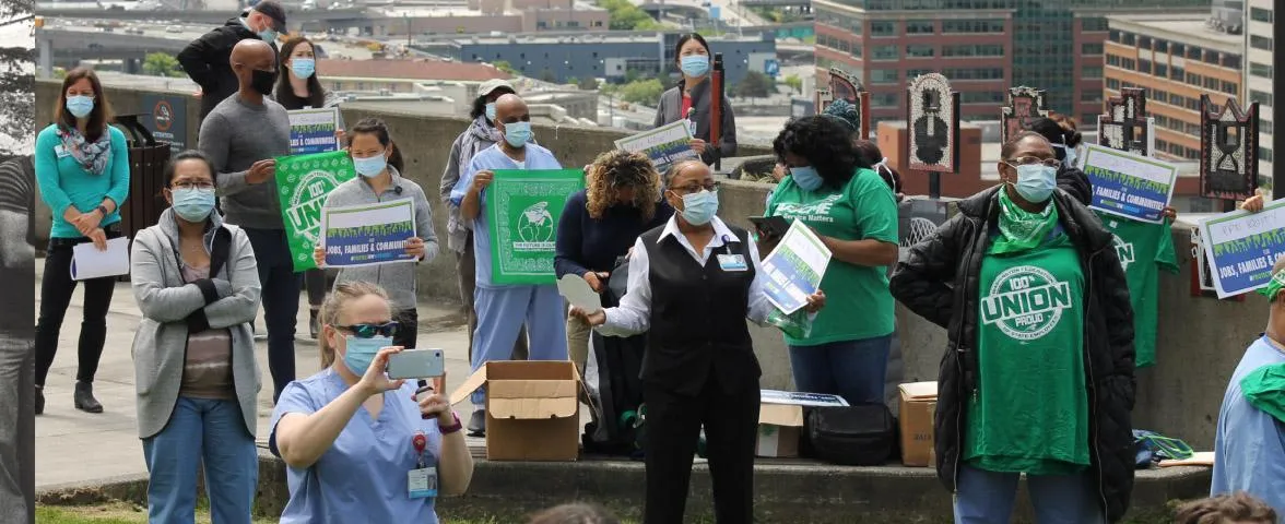 Several people wearing face masks at a rally with a speaker in the center. 