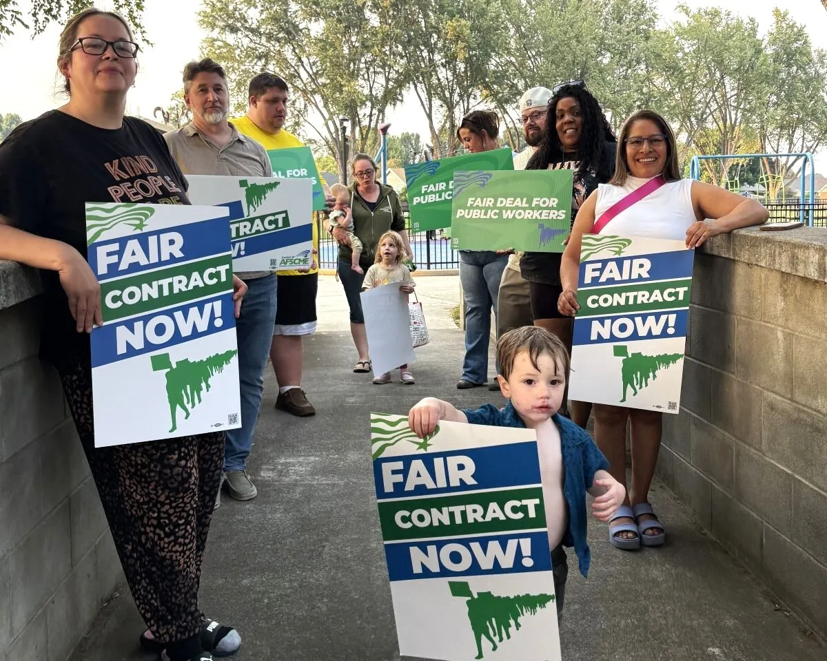 members and their families holding signs demanding fair pay