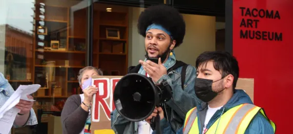 Photo of workers in front of the Tacoma Art Museum with a megaphone and rally signs