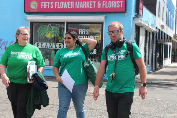 Image of Gabriella Pagdilao-Duras and two union siblings wearing green WFSE shirts and walking during a community outreach event during the recent contract campaign